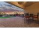 This covered patio features brick pavers, bar height seating, and views of the lush green backyard at 18033 W Tecoma Rd, Goodyear, AZ 85338