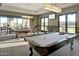 Billiard room featuring two pool tables, modern lighting, and scenic views from the expansive windows at 18123 W Hiddenview Dr, Goodyear, AZ 85338