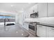 Well-lit kitchen with stainless steel appliances, white cabinetry, gray counters, and lots of storage at 18123 W Hiddenview Dr, Goodyear, AZ 85338