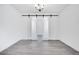 Bright room with sleek hardwood-style floors, neutral walls, barn doors, and a modern chandelier at 18123 W Hiddenview Dr, Goodyear, AZ 85338