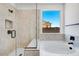 A modern bathroom with a glass shower door, soaking tub, and a bright window at 18150 W Tanglewood Dr, Goodyear, AZ 85338