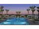 Luxurious community pool surrounded by swaying palm trees, elegant cabanas, and comfortable lounge chairs at twilight at 1919 W Hide Trl, Phoenix, AZ 85085