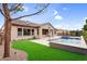 Well-manicured backyard with artificial turf, a sparkling pool, and views of the home's stucco facade at 22296 E Maya Rd, Queen Creek, AZ 85142