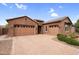 Craftsman home featuring a brick facade, well-manicured yard, and paver driveway leading to a three-car garage at 22296 E Maya Rd, Queen Creek, AZ 85142