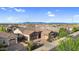 Well-manicured home with a three-car garage and brick-paved driveway, showcasing attractive landscaping and serene mountain views at 22296 E Maya Rd, Queen Creek, AZ 85142
