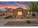 Charming home with brick facade, complemented by desert landscaping and a beautiful sunset at 22296 E Maya Rd, Queen Creek, AZ 85142