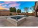 A backyard pool features a travertine patio and spa with serene desert landscaping and a backdrop of colorful sunset skies at 22296 E Maya Rd, Queen Creek, AZ 85142