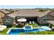 An aerial view showcases the backyard, equipped with a jacuzzi, pool with bar stools, and an umbrella-covered seating area at 22302 E Russet Rd, Queen Creek, AZ 85142