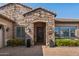 Inviting stone entryway with a wrought iron door, decorative plants, and stylish lighting fixtures at 22302 E Russet Rd, Queen Creek, AZ 85142