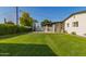 Spacious backyard featuring a manicured lawn, covered patio, and tall hedge for enhanced privacy at 2236 W Shaw Butte Dr, Phoenix, AZ 85029