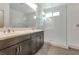 Modern bathroom featuring double sinks, dark cabinetry, and a glass-enclosed shower with tiled walls at 2491 N 149Th Ln, Goodyear, AZ 85395