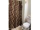 Close-up shot of toilet and patterned shower curtain in bathroom with neutral colors at 3020 N 64Th Dr, Phoenix, AZ 85033