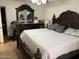 A spacious primary bedroom showcasing an ornate wooden bed frame and matching dresser with mirror at 3020 N 64Th Dr, Phoenix, AZ 85033