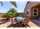 Outdoor dining area with seating for four, set against a backdrop of tropical landscaping and hot tub at 37852 W Merced St, Maricopa, AZ 85138