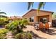 Outdoor patio with a dining table surrounded by lush landscaping, creating a serene backyard escape at 37852 W Merced St, Maricopa, AZ 85138