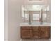 Bright bathroom featuring a dual sink vanity, large mirrors, and oak wood cabinets at 37852 W Merced St, Maricopa, AZ 85138