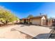 Exterior view of a home with a wide driveway, desert landscaping, and a covered front porch with chairs at 411 N 111Th Pl, Mesa, AZ 85207