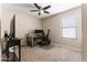 Bedroom showcasing a ceiling fan, large window, and dedicated desk area for an office at 42430 W Oakland Dr, Maricopa, AZ 85138