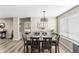 Dining area with wood-look floors, modern light fixture, and a view into the main bedroom at 42430 W Oakland Dr, Maricopa, AZ 85138