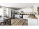 Bright eat-in kitchen with white cabinets, stainless appliances, and wood-look floors and adjacent dining area at 42430 W Oakland Dr, Maricopa, AZ 85138