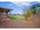 An expansive backyard featuring gravel landscaping, mature trees, and a covered patio at 6120 W Keim Dr, Glendale, AZ 85301