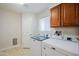 Bright laundry room with tile floors, white appliances, and storage cabinets overhead at 6120 W Keim Dr, Glendale, AZ 85301