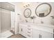 Modern bathroom featuring a double sink vanity, round mirrors, and a separate shower with stylish tiling at 6130 E Windsor Ave, Scottsdale, AZ 85257