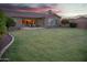Sprawling backyard with a manicured lawn, mature trees, an outdoor patio, and a lovely desert sunset in the background at 15664 W Vernon Ave, Goodyear, AZ 85395