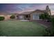 Large backyard with lush green lawn, mature trees, and a covered patio with outdoor seating, perfect for entertaining at 15664 W Vernon Ave, Goodyear, AZ 85395