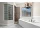 Luxurious bathroom showcasing a standalone tub next to a glass block window, a separate tiled shower, and a chandelier at 15664 W Vernon Ave, Goodyear, AZ 85395