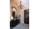 Inviting entryway features a dark wood front door, decorative mirror, elegant chandelier, and beautiful decor at 15664 W Vernon Ave, Goodyear, AZ 85395