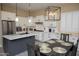 Modern kitchen with white cabinets, stainless steel appliances, an island, and a stylish light fixture at 15664 W Vernon Ave, Goodyear, AZ 85395