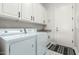 Bright laundry room with white cabinets, appliances, and an exterior door at 15664 W Vernon Ave, Goodyear, AZ 85395