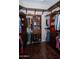 Spacious walk-in closet with wood shelving, hanging rods, dark wood flooring, and ample storage space for clothes and accessories at 15664 W Vernon Ave, Goodyear, AZ 85395