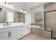 Bathroom featuring dual sinks, large mirror, soaking tub, and separate shower at 24054 N 171St Dr, Surprise, AZ 85387