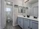 Bright bathroom with dual sinks, blue vanity cabinets, and a doorway leading to the shower area at 1282 W Kesler Ln, Chandler, AZ 85224