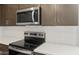 Close-up on stainless steel microwave and stovetop with modern white subway tile backsplash at 17770 W Getty Dr, Goodyear, AZ 85338