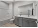 Bright bathroom featuring double vanity with gray cabinets and a shower-tub combination at 17791 W Getty Dr, Goodyear, AZ 85338