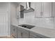Close-up view of kitchen showcasing the quartz countertops, designer backsplash and stainless steel range hood at 17791 W Getty Dr, Goodyear, AZ 85338