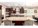 Modern kitchen featuring a large granite island, stainless steel appliances, dark wood cabinets, and pendant lighting at 18543 W Denton Ave, Litchfield Park, AZ 85340