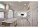 Kitchen with a center island, white cabinetry, arched windows, and open layout to the living room at 2009 N 125Th Ave, Avondale, AZ 85392