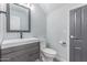 Modern half bathroom features a stylish vanity, toilet, and gray accent wall at 21121 N 63Rd Dr, Glendale, AZ 85308