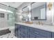 Modern bathroom featuring double sinks, marble countertops, and a sleek glass shower with a gray tile surround at 21121 N 63Rd Dr, Glendale, AZ 85308