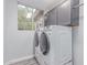 Bright laundry room showcasing a front-load washer and dryer, complemented by upper cabinets and a window at 21121 N 63Rd Dr, Glendale, AZ 85308