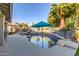 Inviting pool area with natural stone accents, a rock waterfall feature, mature landscaping, and a blue umbrella at 21121 N 63Rd Dr, Glendale, AZ 85308