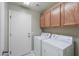 Well-lit laundry room with washer, dryer, tile flooring, cabinets, and convenient access door at 2384 E Santiago Trl, Casa Grande, AZ 85194