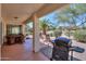 Inviting covered patio with dining set, outdoor seating, and grill overlooking lush landscaping at 2464 E Hancock Trl, Casa Grande, AZ 85194
