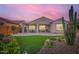 Twilight view of landscaped backyard with patio, turf, desert plants and covered seating area at 25920 W Westcott Dr, Buckeye, AZ 85396