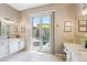 Bright bathroom with granite countertops, white cabinets, and sliding glass door to the outside patio at 27688 N 125Th Dr, Peoria, AZ 85383