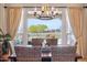 Elegant dining area with a charming chandelier, natural light, and views of the backyard at 27688 N 125Th Dr, Peoria, AZ 85383